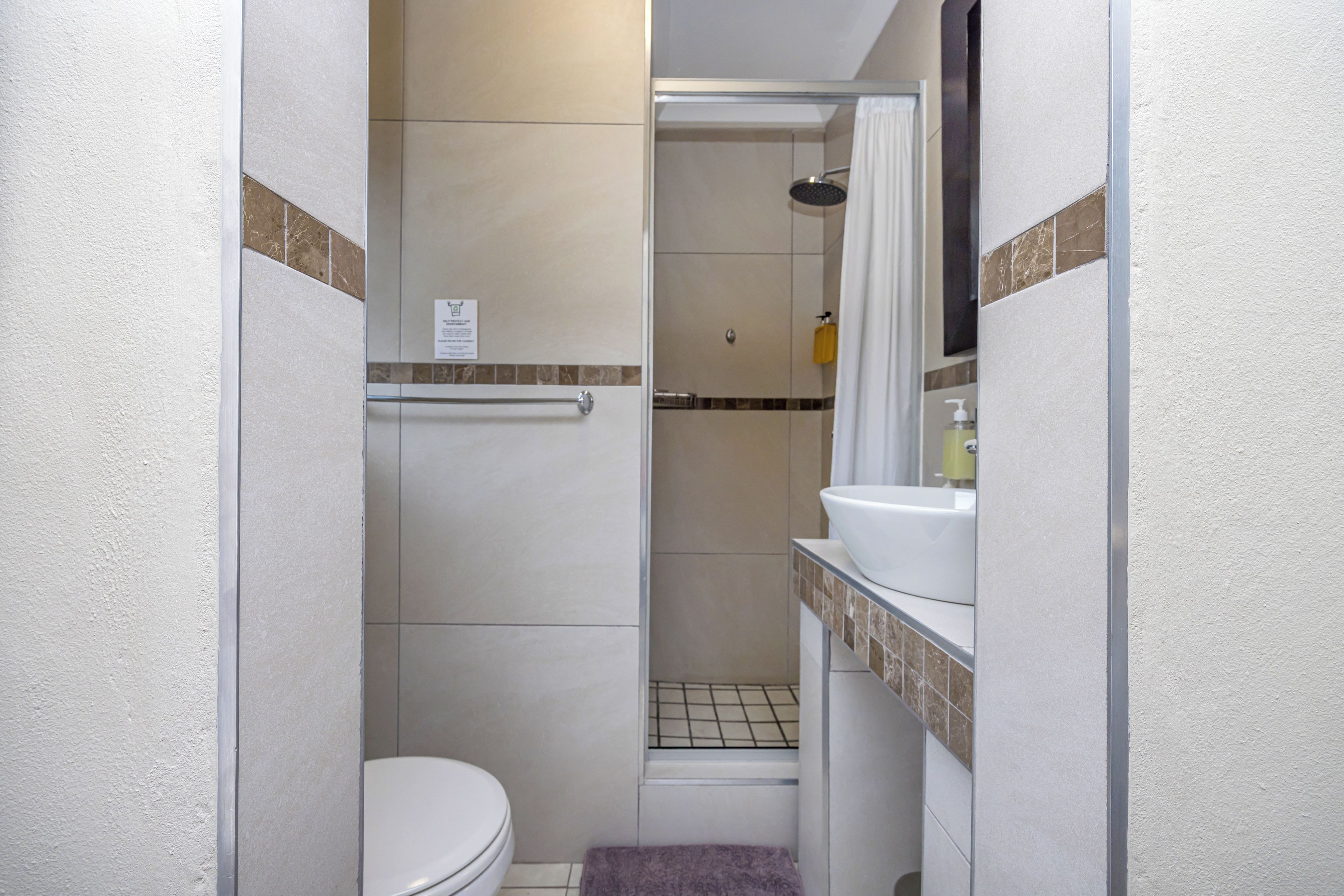 A compact bathroom with a toilet, shower, and sink.