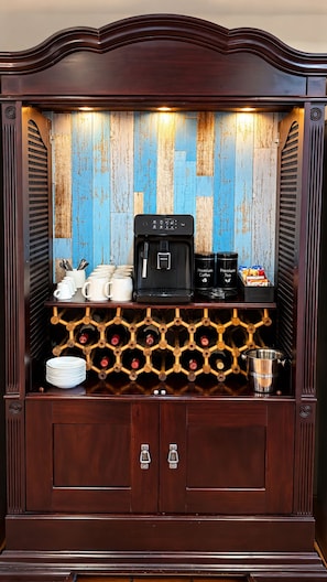 Eine Kaffeestation mit Kaffeemaschine, Tassen und einem Weinregal.