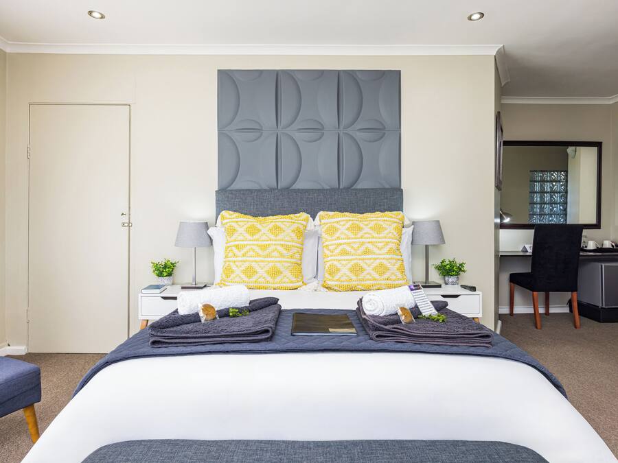 Une chambre d’hôtel avec un grand lit, deux tables de chevet, un bureau, une chaise et un miroir.