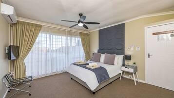A hotel room with a bed, bedside table, nightstand, and a ceiling fan.