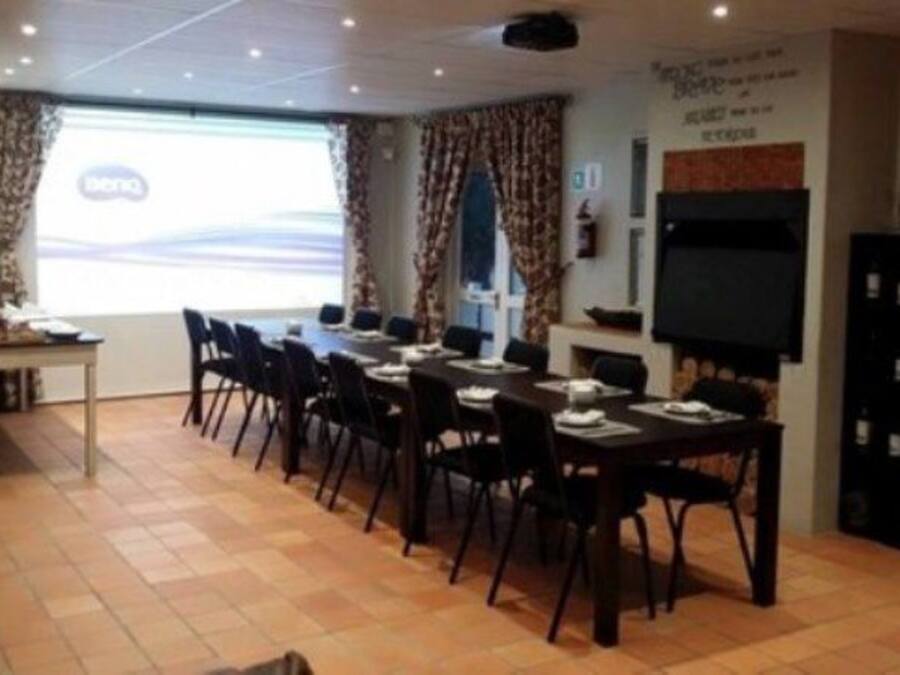 A conference room with a long table, chairs, a projector screen, and a television.