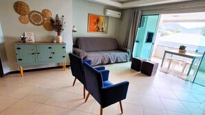 A modern living room with a sofa, a dining table, and a cabinet. - Apartamento do Sol (Bombinhas)