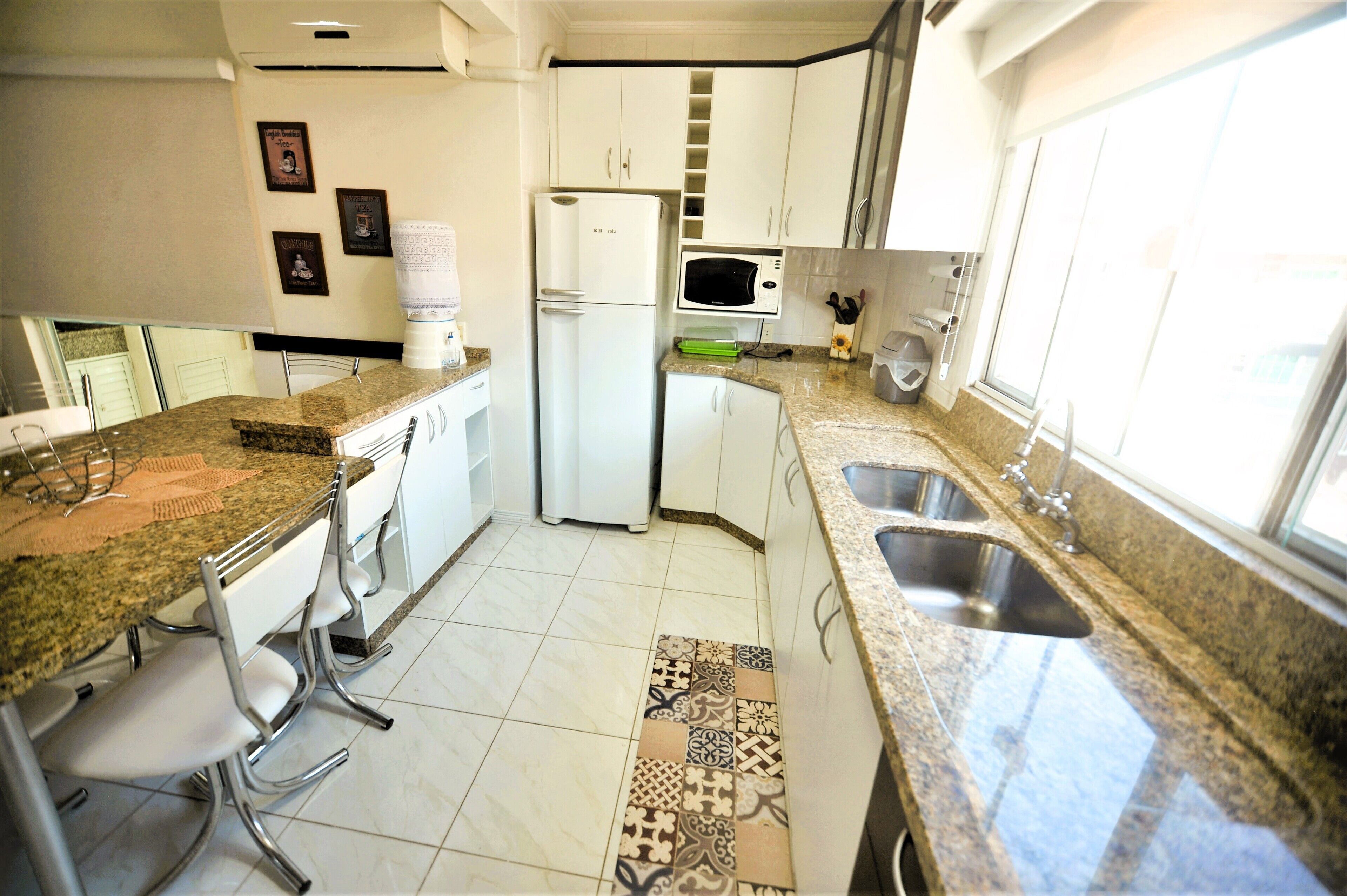 A kitchen with white cabinets, a refrigerator, a microwave, and a sink.