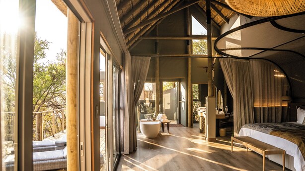A spacious bedroom with a large bed, a sitting area, and a view of the outdoors.