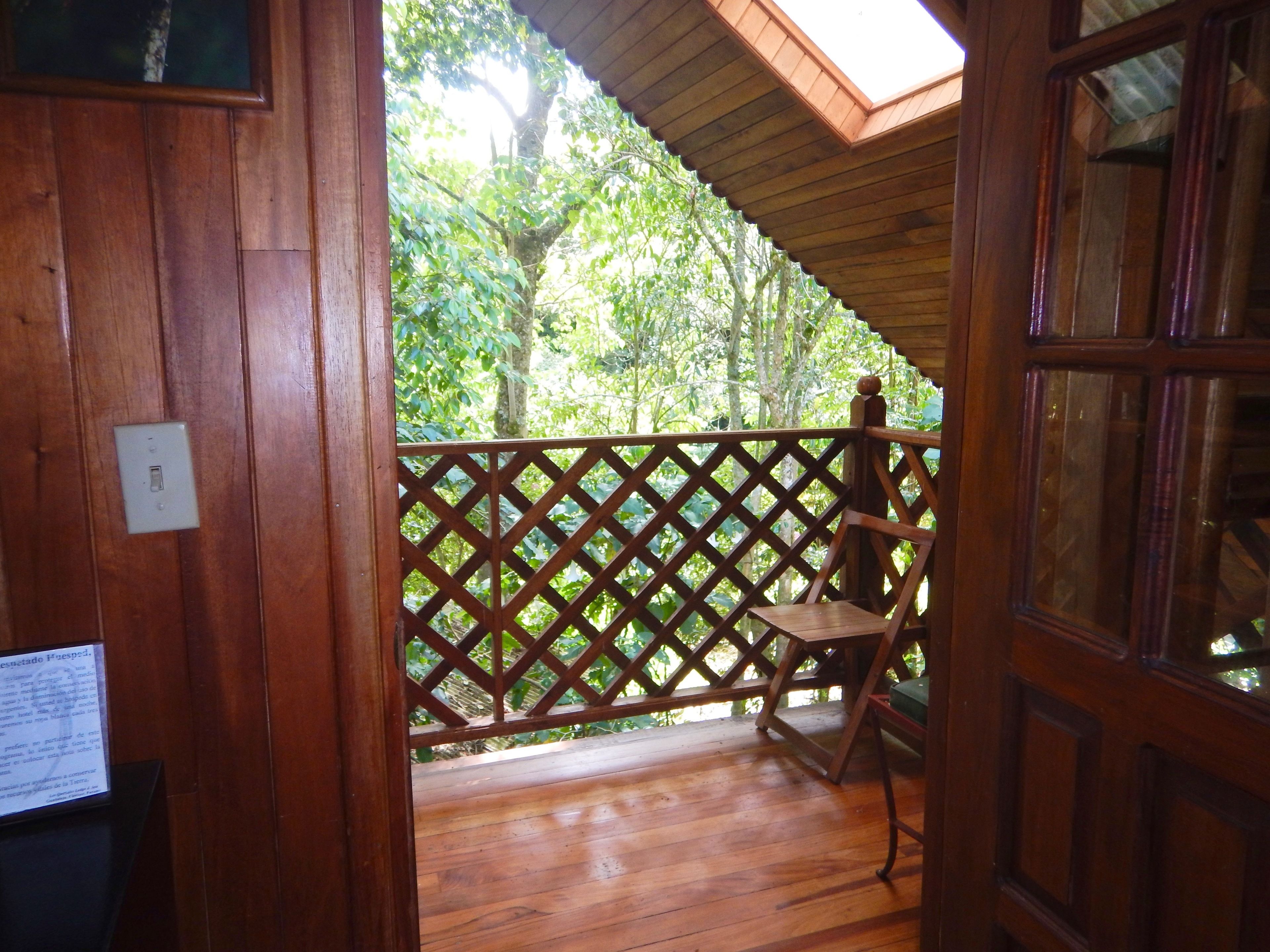 Un balcon en bois avec une balustrade en treillis, une chaise et un plancher en bois.