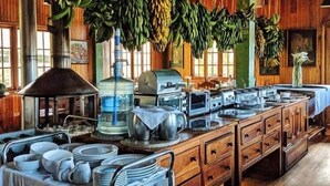 A large dining hall with wooden beams, hanging bananas, and a buffet setup with various dishes and utensils. - Los Quetzales Ecolodge & Spa (Cerro Punta)