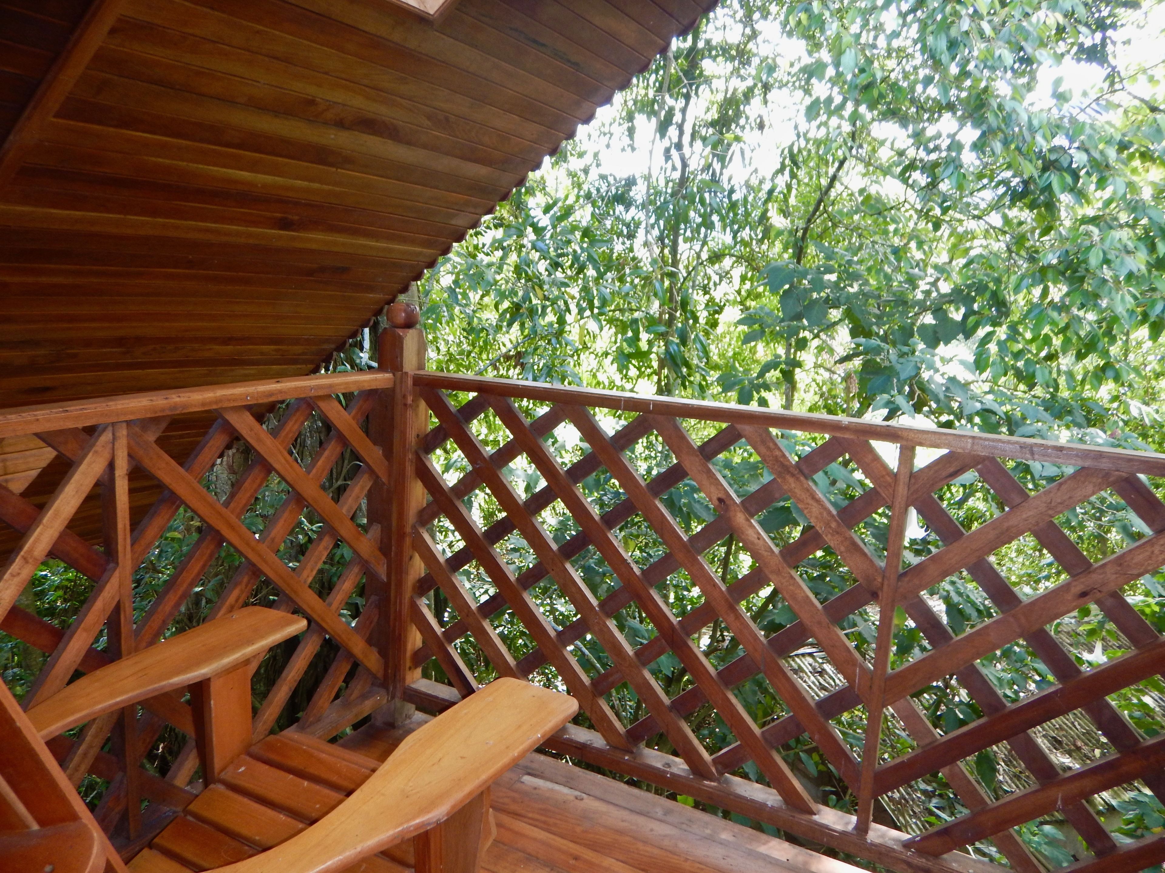 Una terraza de madera con barandilla enrejada y un banco.