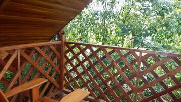 Una terraza de madera con barandilla enrejada y un banco.