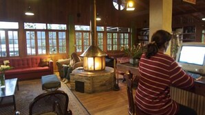 A cozy interior with a fireplace, wooden furniture, and large windows. - Los Quetzales Ecolodge & Spa (Cerro Punta)