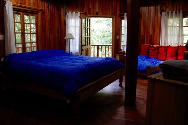 A room with a large bed, a smaller sofa, and a wooden floor. - Los Quetzales Ecolodge & Spa (Cerro Punta)