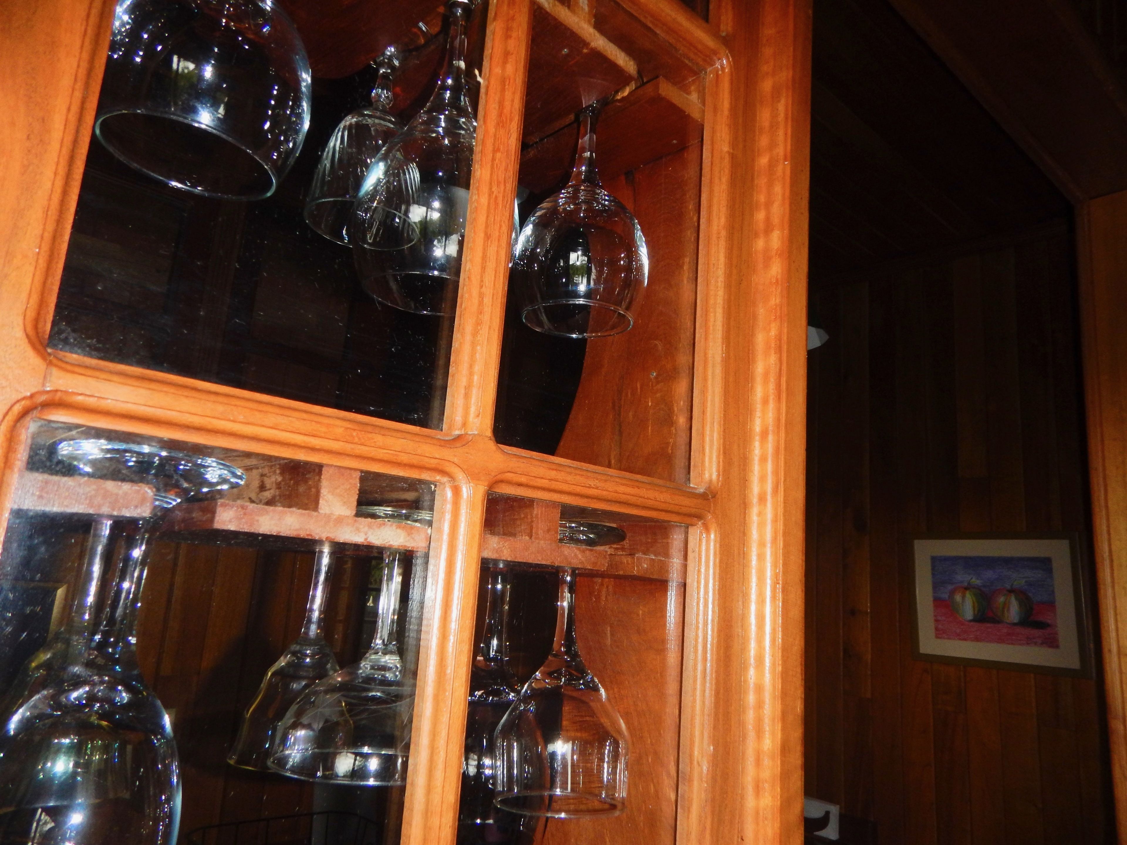 Un mueble de madera con varios vasos de vino colgando en su interior.