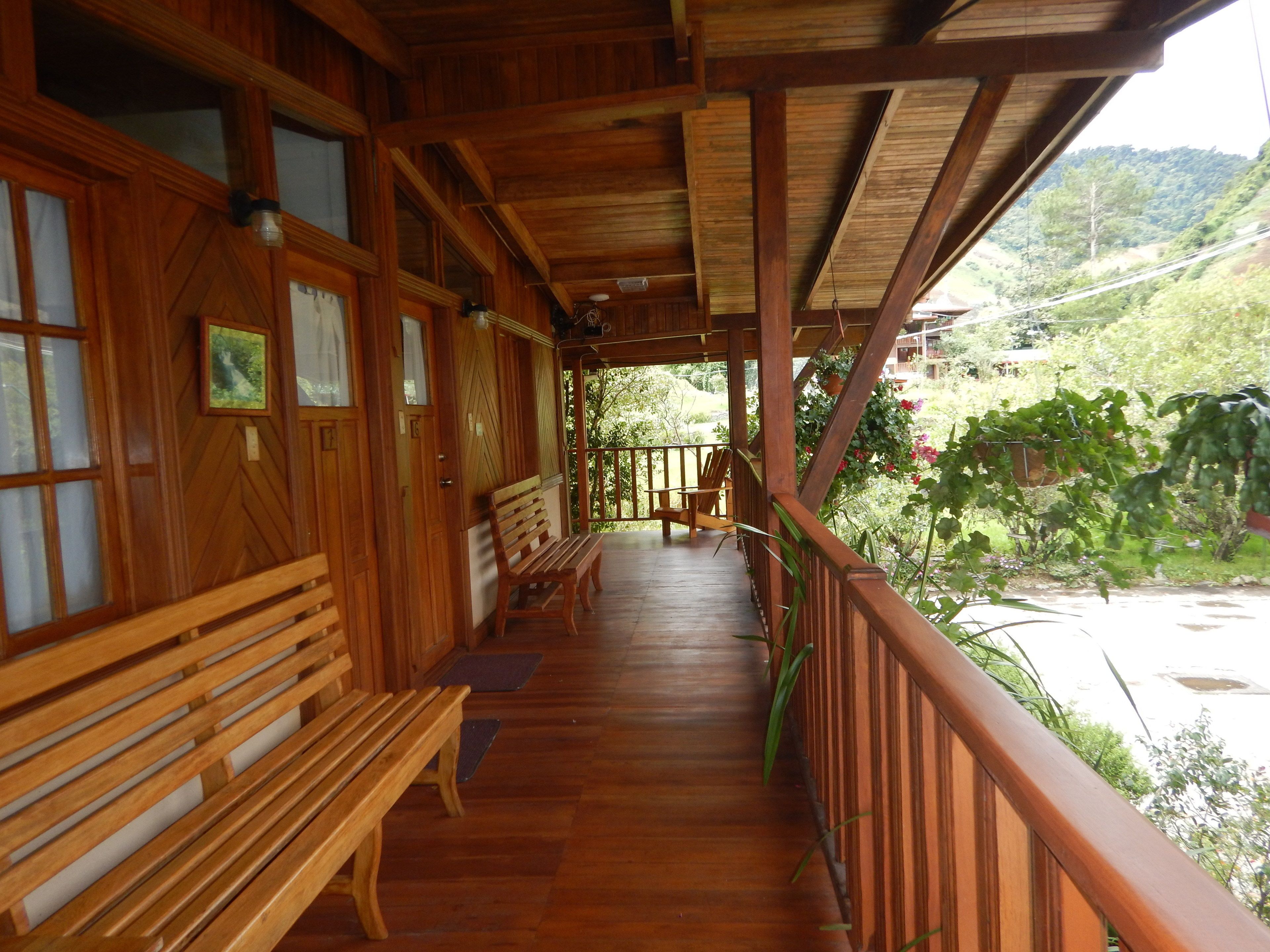 A wooden porch with benches and a view of a lush green landscape.