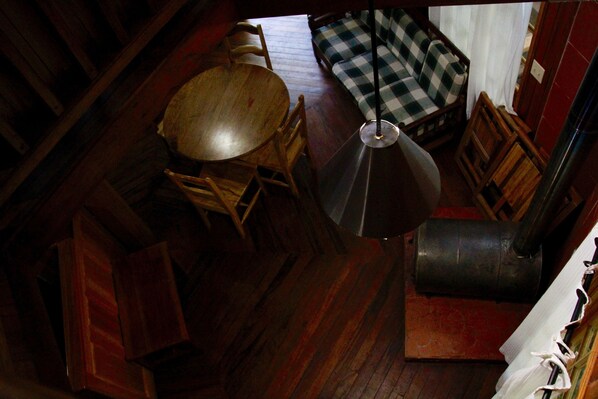 Una habitación con una mesa de comedor de madera, sillas, un sofá a cuadros y una lámpara de pie.
