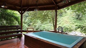 A covered outdoor swimming pool with wooden benches and a view of a lush forest. - Los Quetzales Ecolodge & Spa (Cerro Punta)