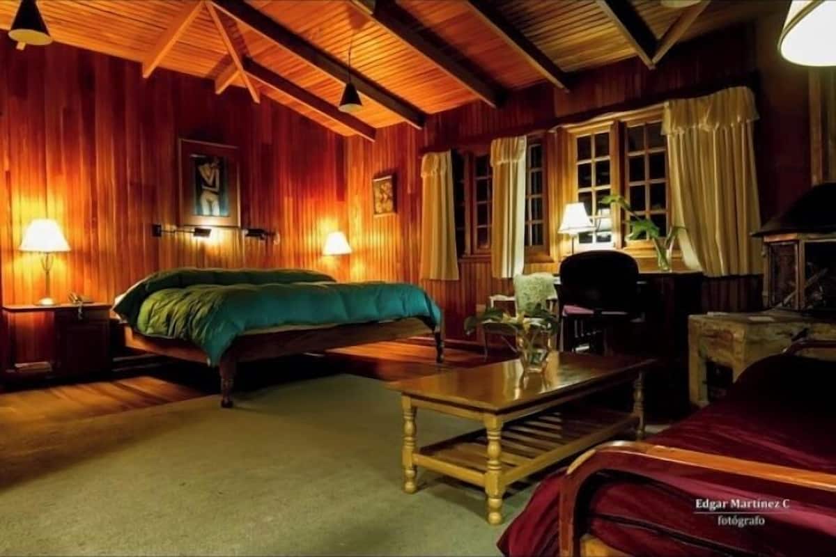 A cozy room with a bed, a wooden table, and a fireplace.