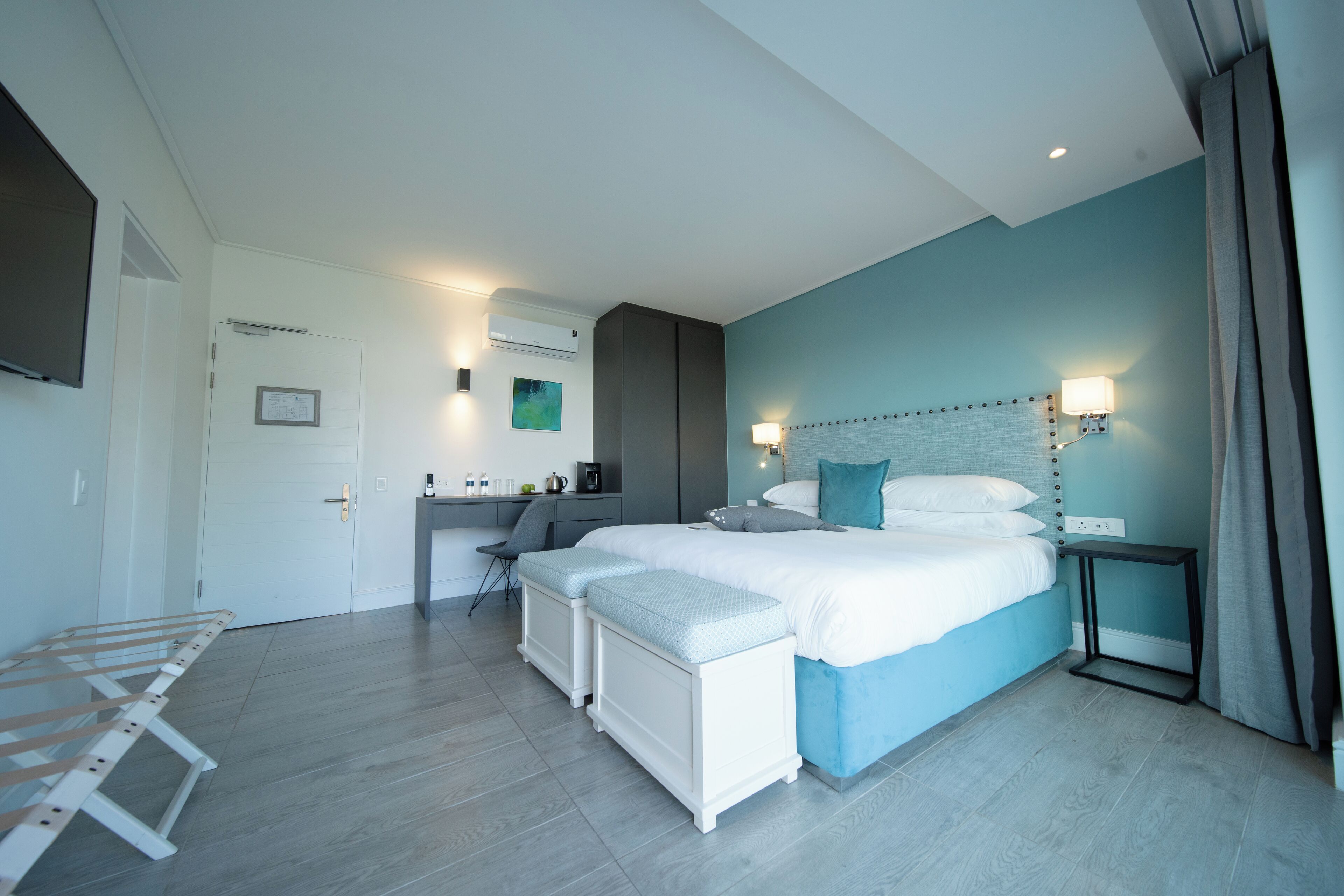 A modern hotel room with a large bed, a desk, and a seating area.