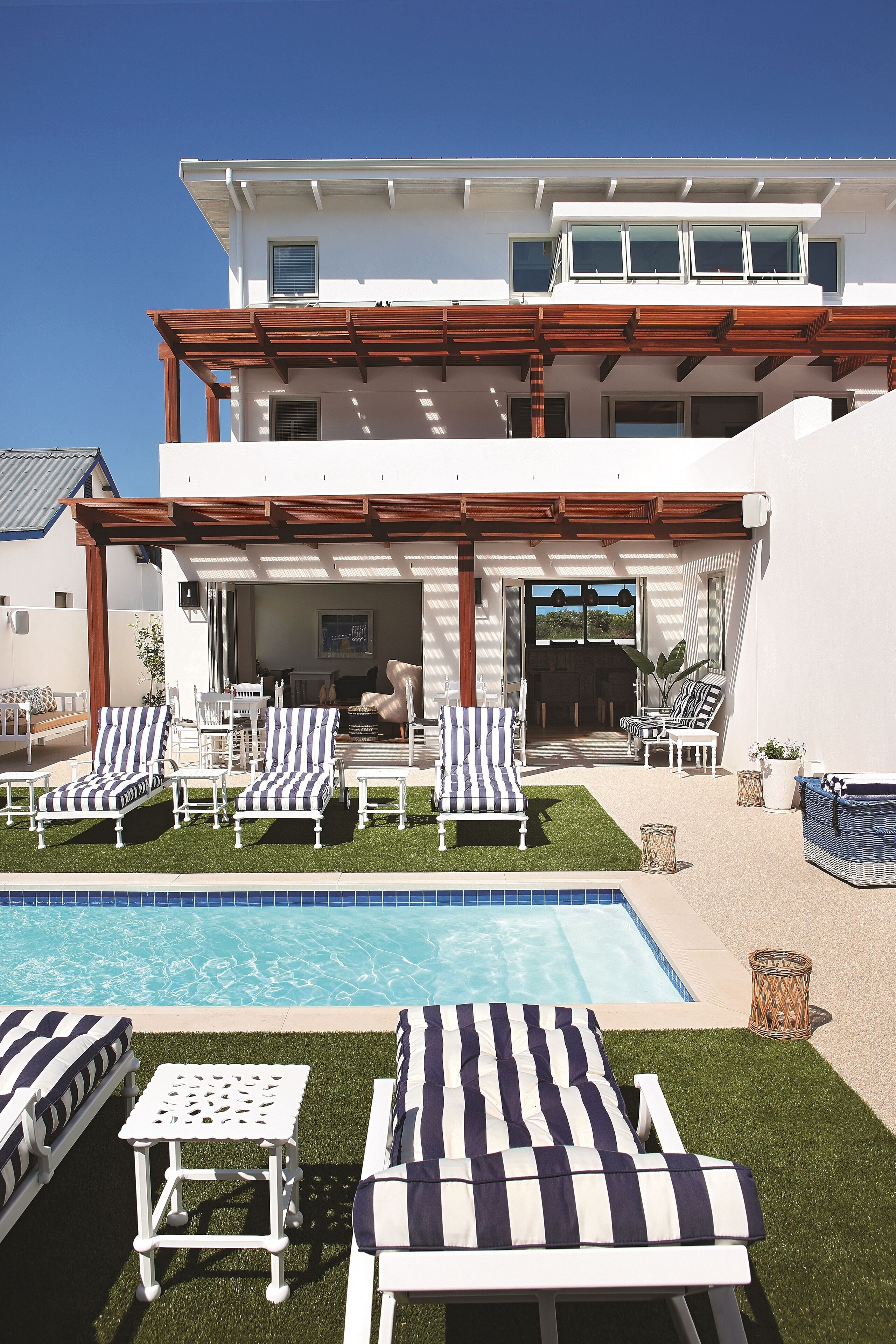 A modern house with a pool, outdoor seating, and a covered patio.