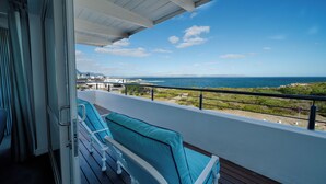 A balcony with a view of the ocean and a distant cityscape.