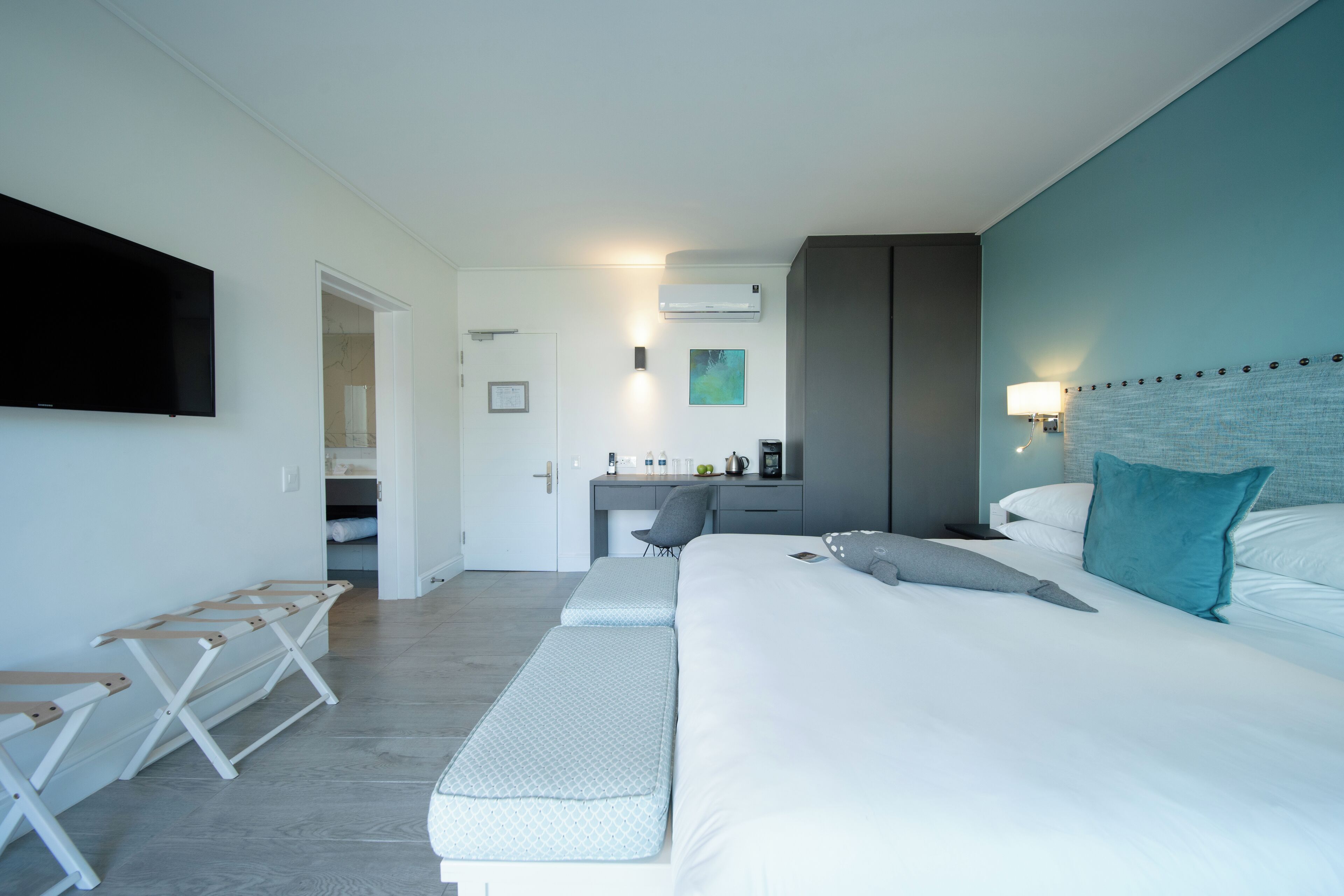 Quarto de hotel moderno com uma cama grande, uma escrivaninha e televisão na parede.