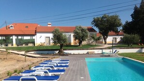 A swimming pool with blue lounge chairs and a wooden deck. - Casa das Rendufas (Torres Novas)