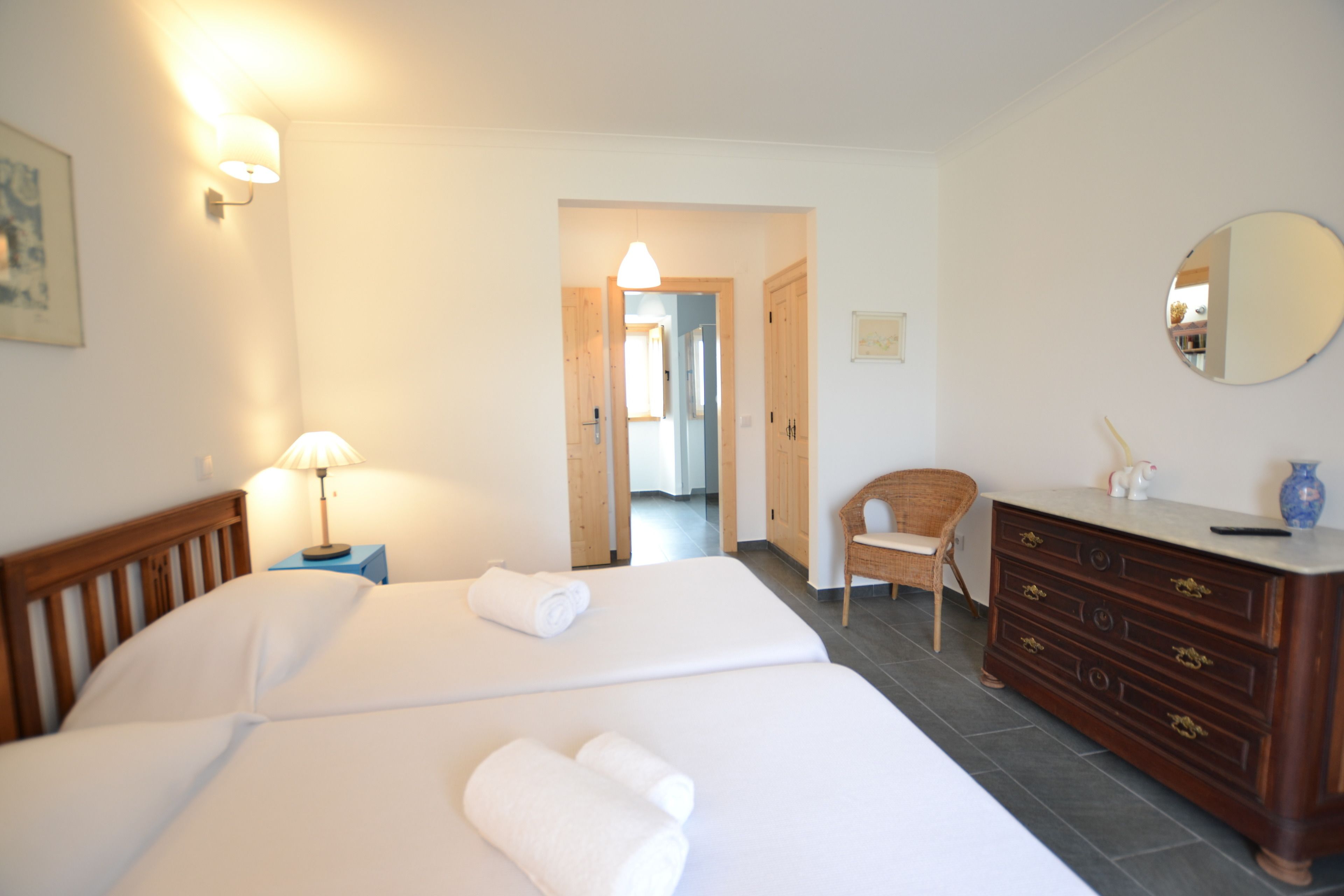 A hotel room with two beds, a dresser, a chair, and a mirror.