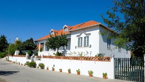 A white building with a red-tiled roof, a balcony, and a fence. - Casa das Rendufas (Torres Novas)