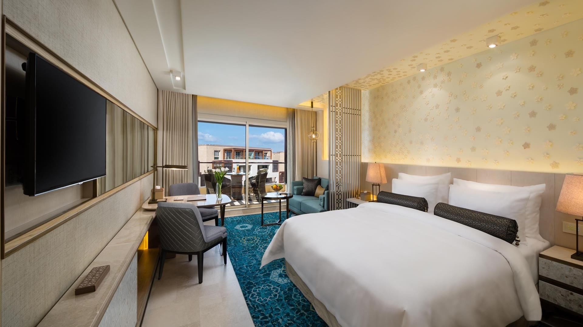 Habitación de hotel con una cama grande, un televisor de pantalla plana, un escritorio con una silla y vistas al exterior.