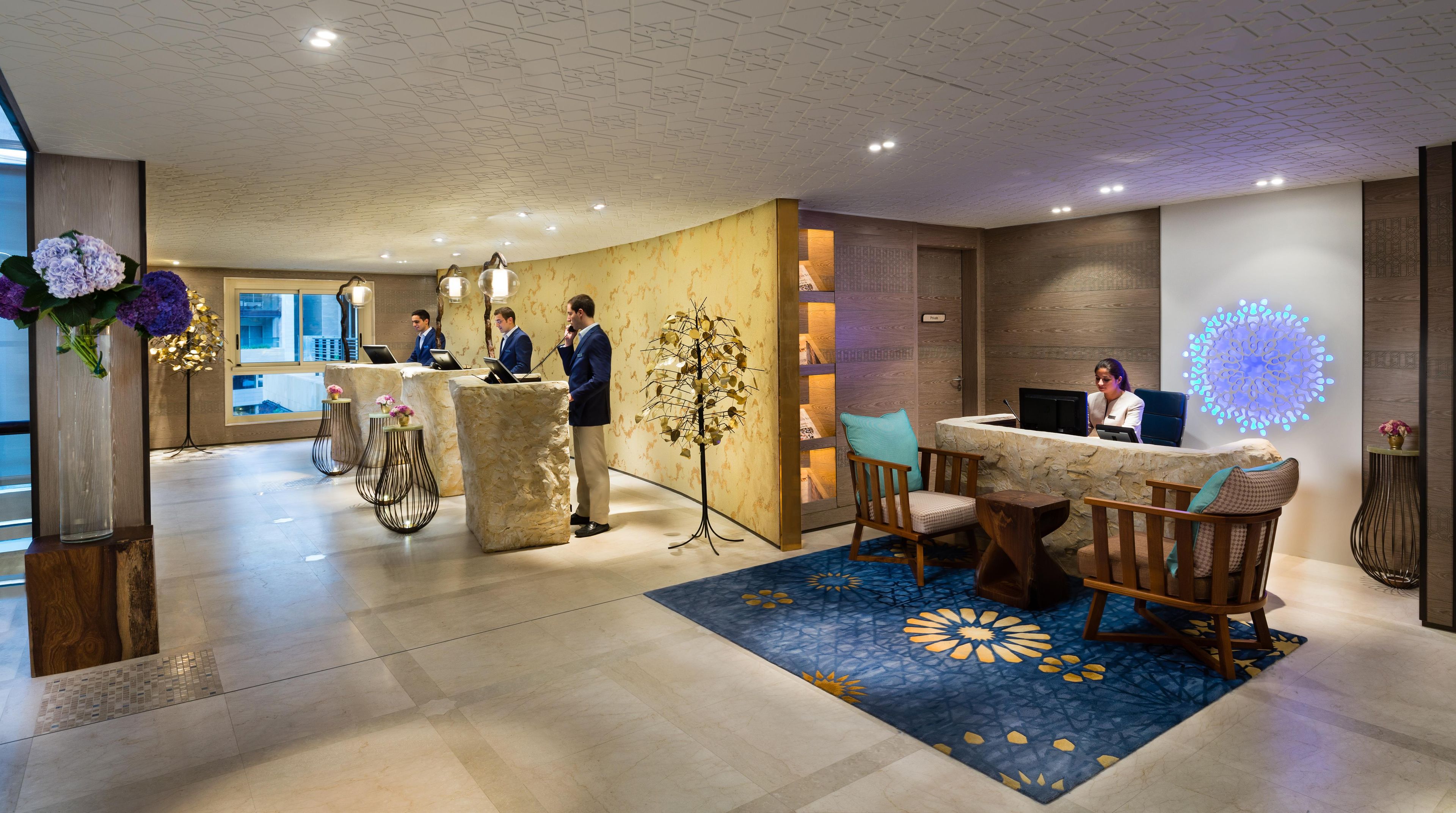 A hotel reception area with a reception desk, seating, and a decorative tree sculpture.
