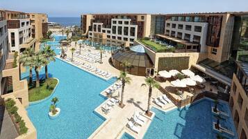 Um resort com várias piscinas, espreguiçadeiras e vista para o oceano.