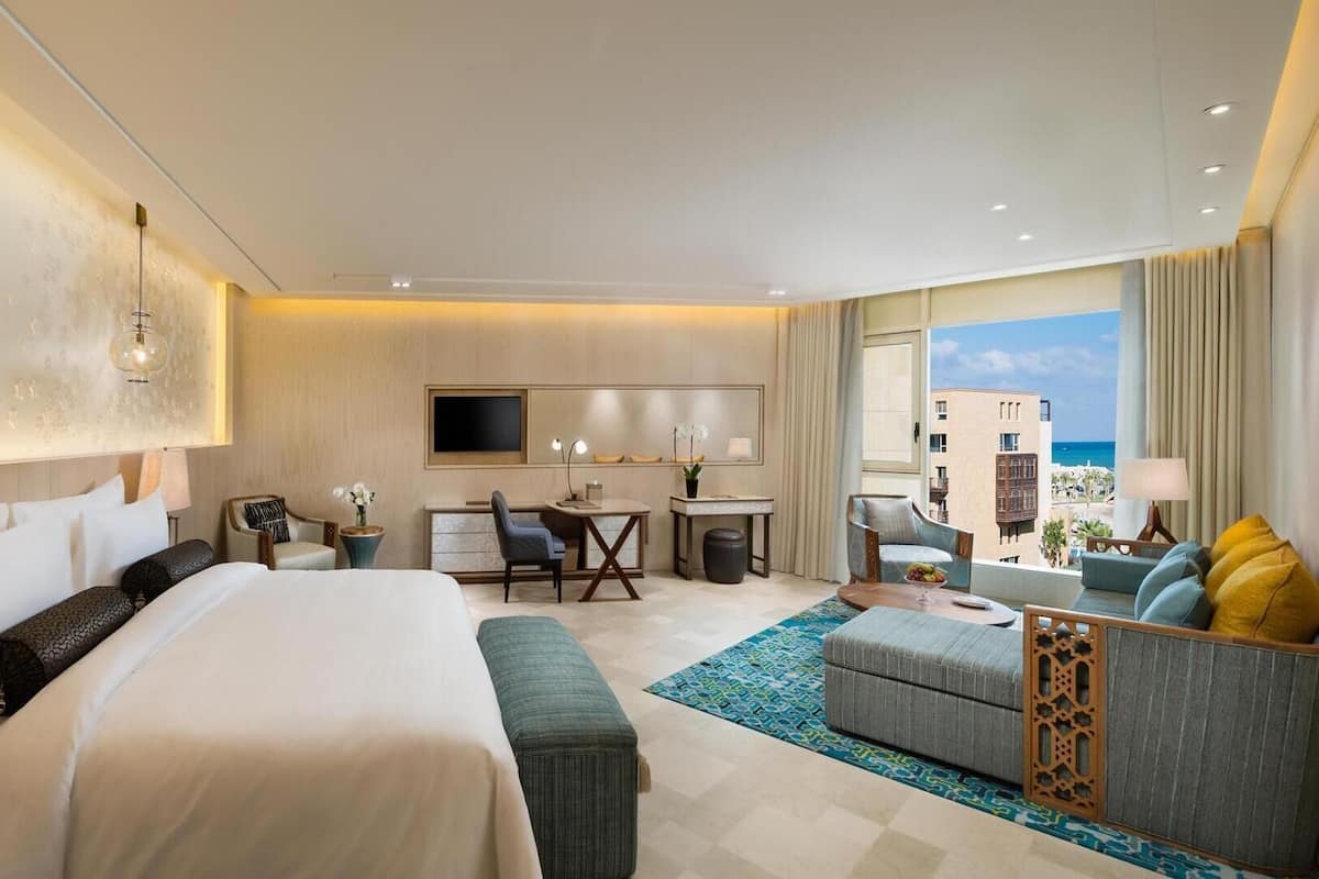 Habitación de hotel moderna con una cama grande, un escritorio, un sofá y vistas a la ciudad.