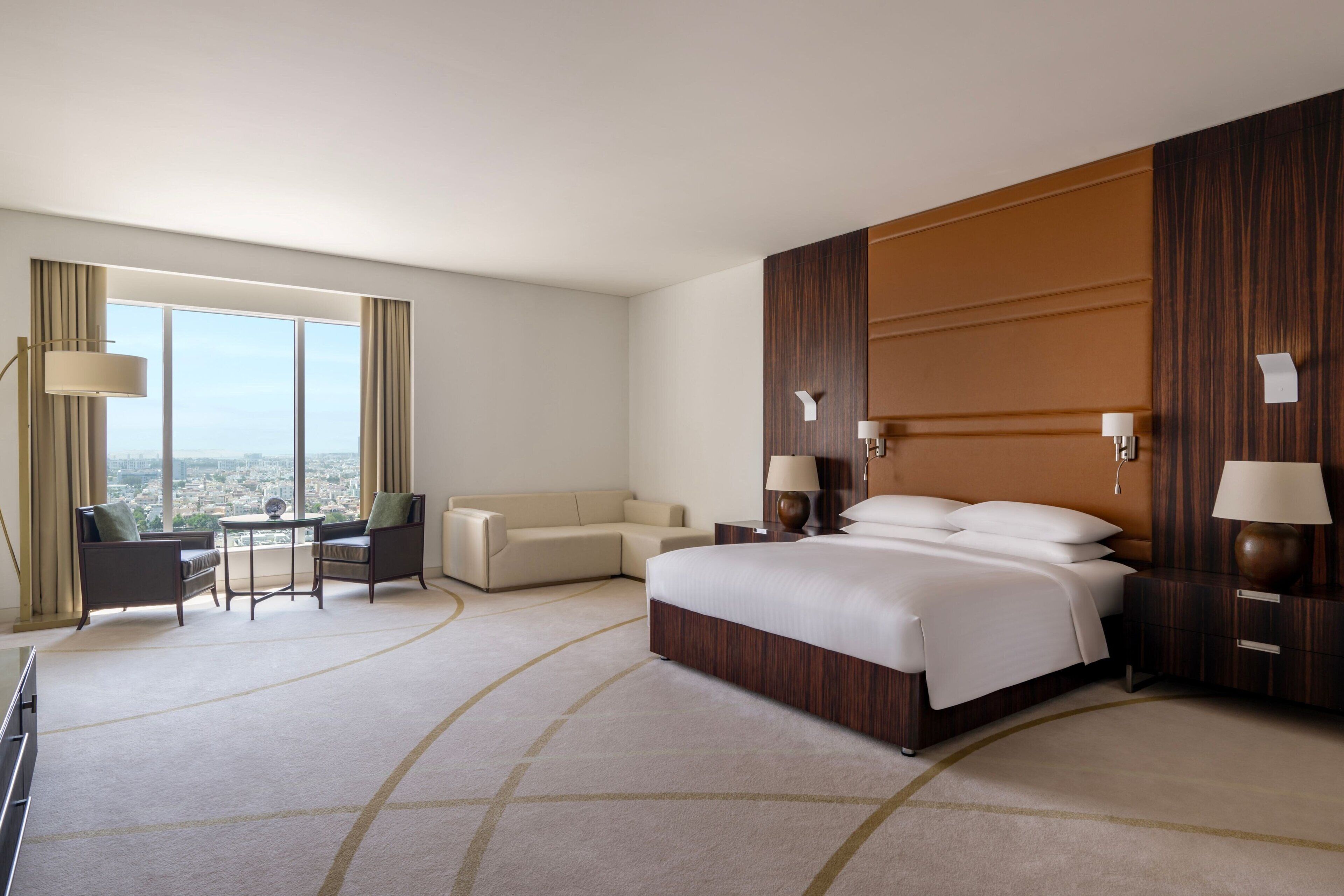 Une chambre d’hôtel avec un grand lit, un canapé, un bureau et une vue sur la ville.