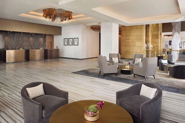 Relax in the hotel's spacious lobby, featuring a reception desk, comfortable seating area, and beautiful artwork on the walls.