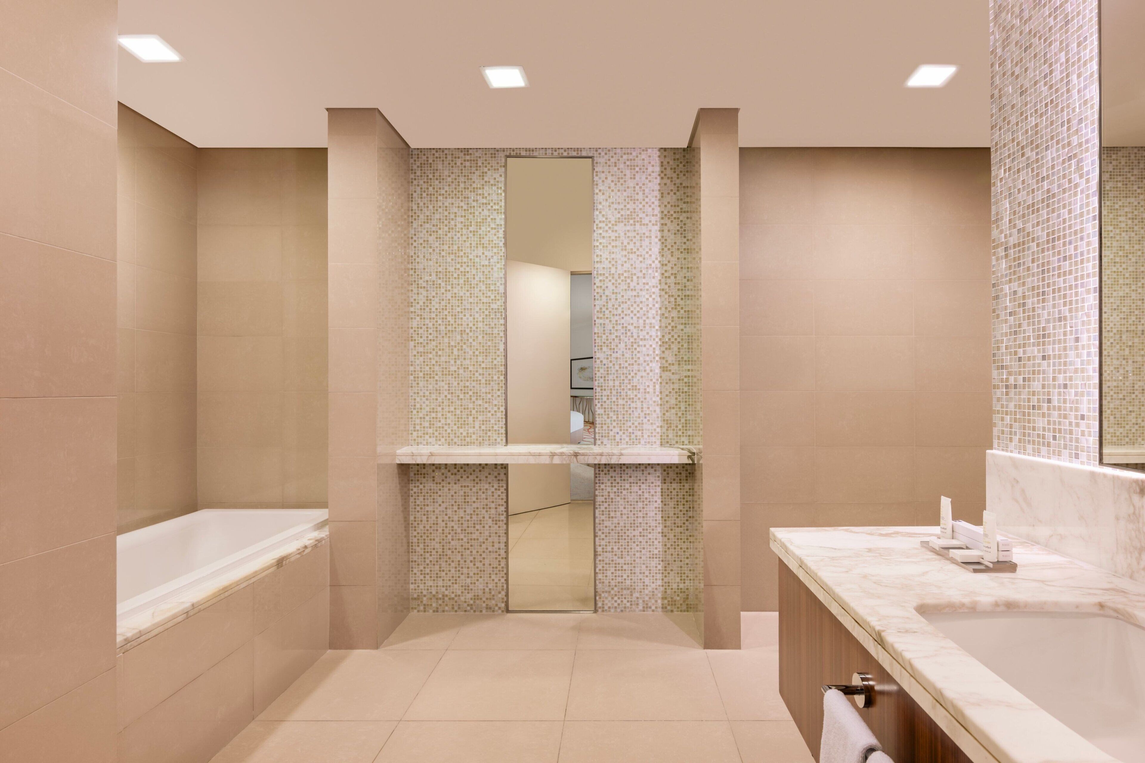 A modern bathroom with a bathtub, a sink, and a mirror.