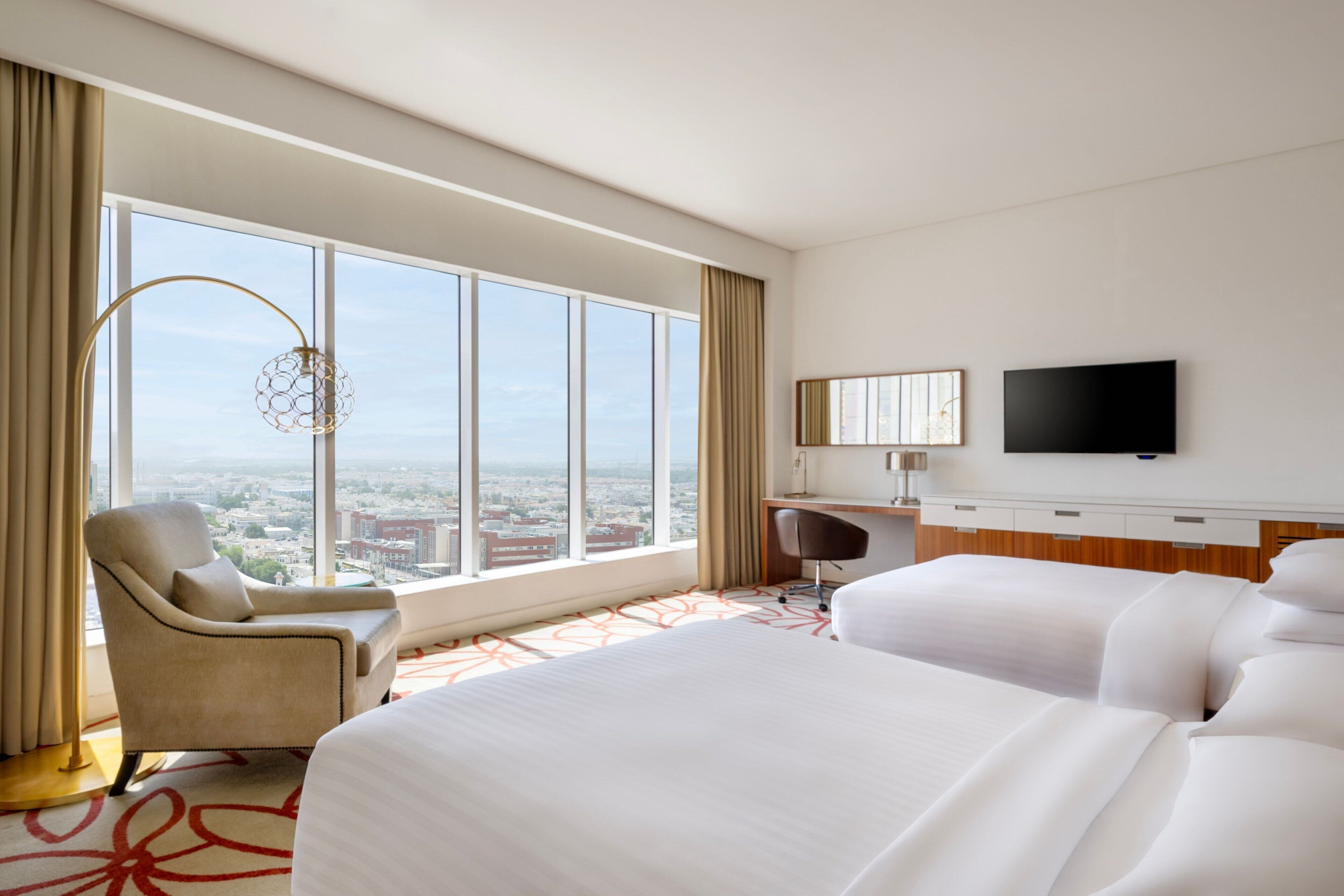 Una habitación de hotel con un ventanal grande, un escritorio, una silla y una cama.