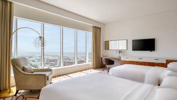 Una habitación de hotel con un ventanal grande, un escritorio, una silla y una cama.