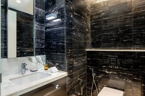 Experience the epitome of luxury in this sleek bathroom, featuring a large mirror, marble countertop, and modern fixtures.