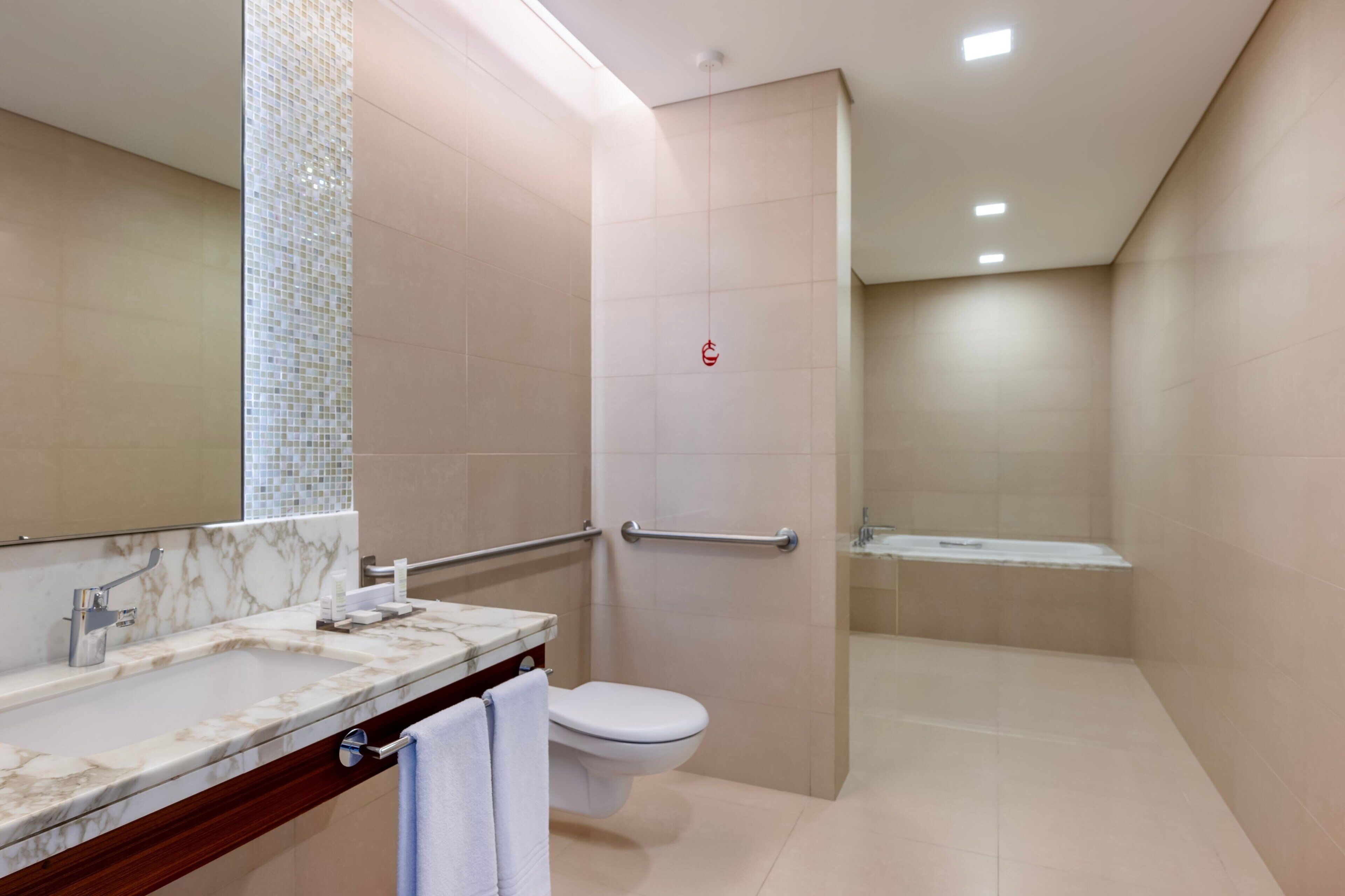 Un baño moderno con lavamanos de mármol, inodoro y zona de ducha.