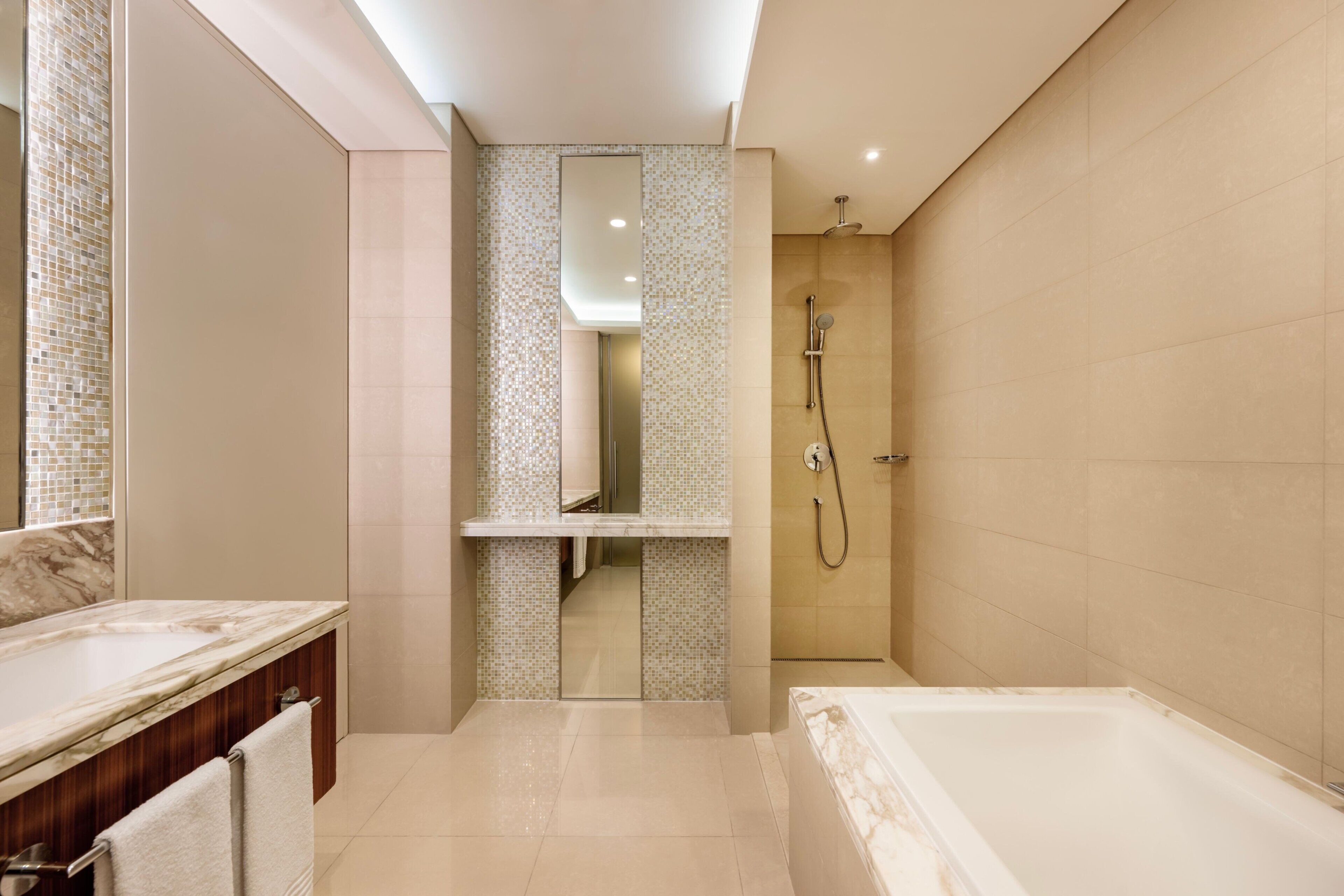 A modern bathroom with a marble sink, a large mirror, a walk-in shower, and a bathtub.