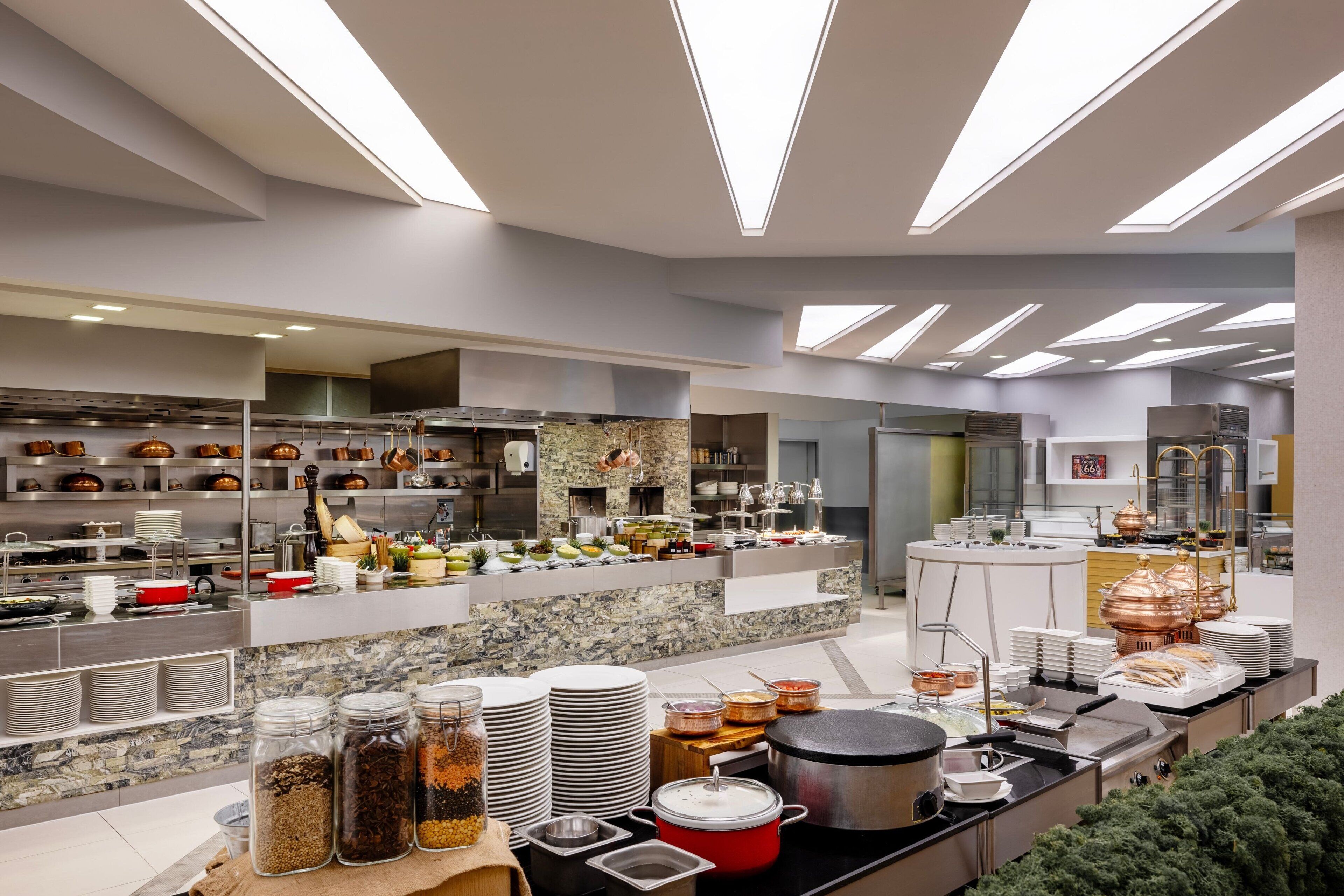 A modern kitchen with stainless steel appliances, a marble backsplash, and a variety of food items and utensils on display.