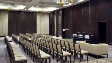 A conference room with rows of chairs and a stage.