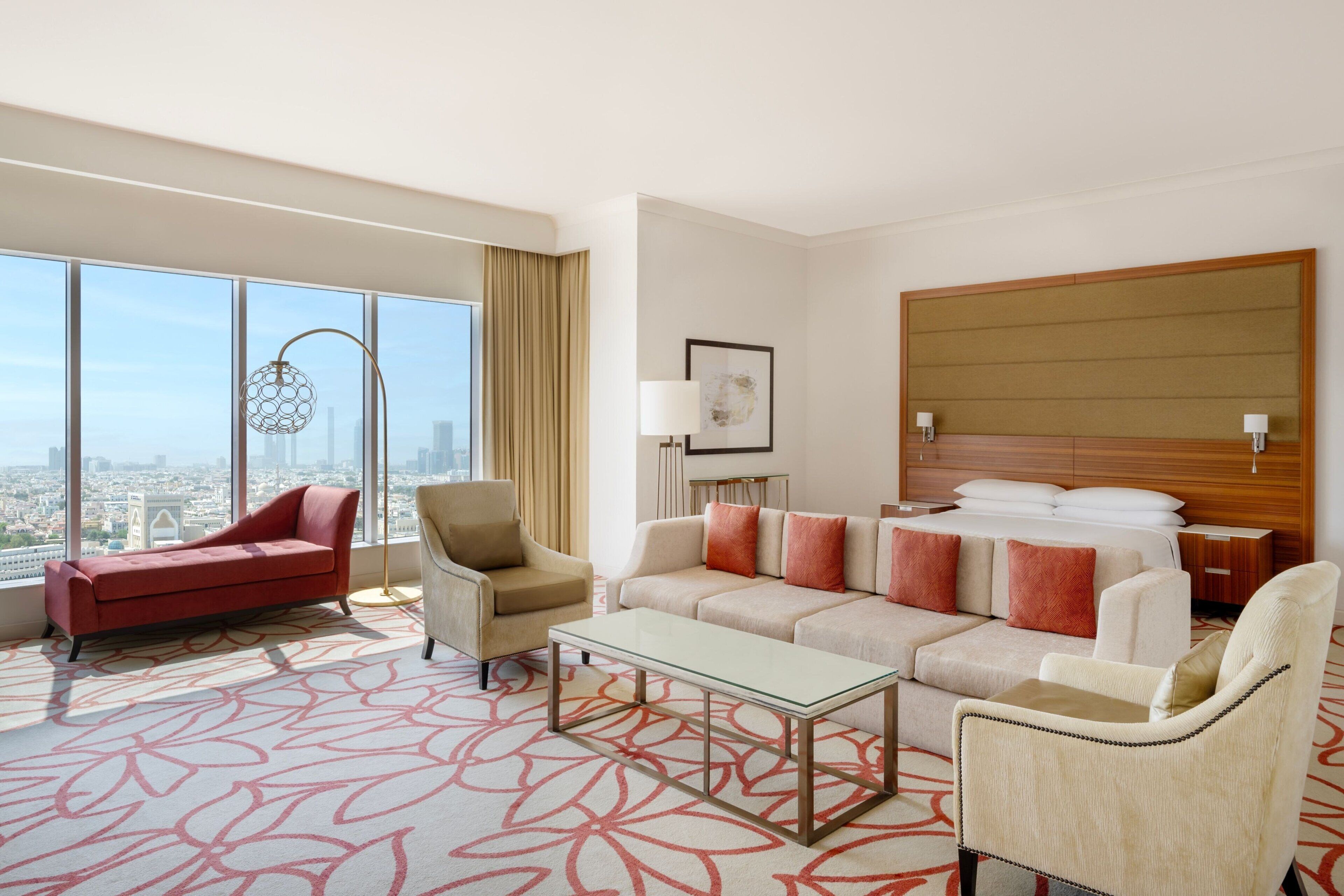 Een hotelkamer met een groot raam, een bank, een stoel, een salontafel en een bed.