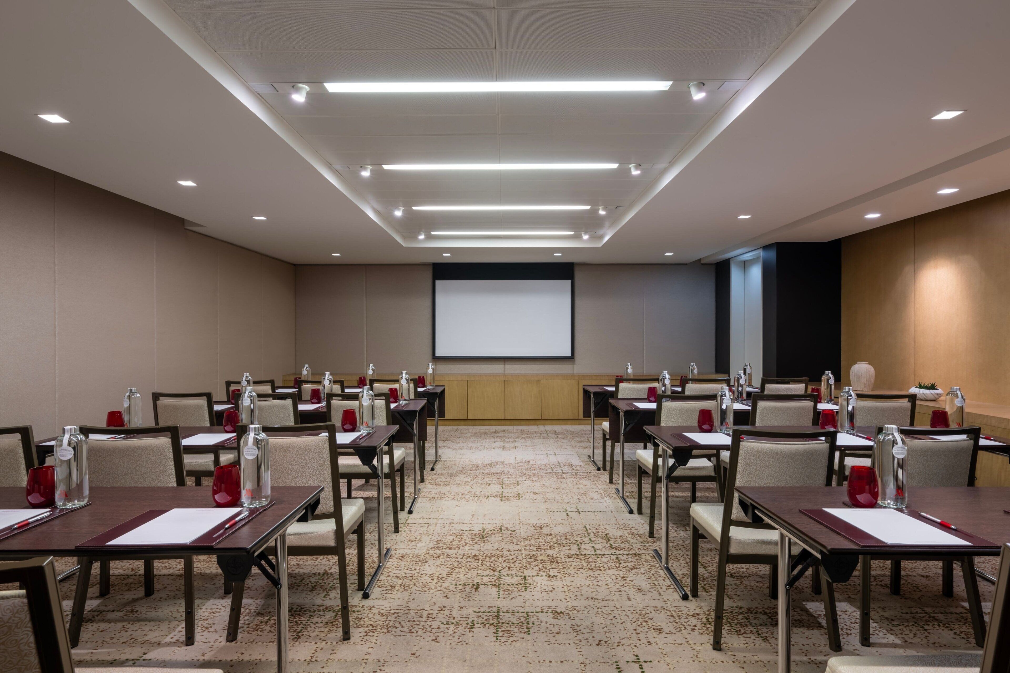 Une salle de conférence équipée de tables, de chaises et d’un écran de projection.