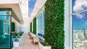 Un espacio interior moderno con pared de vidrio, zona de estar y vistas al horizonte de la ciudad.
