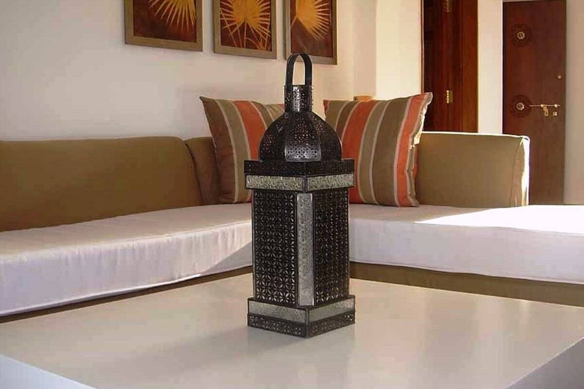 A room with a white table, a decorative lantern, a sofa with striped cushions, and a door in the background.