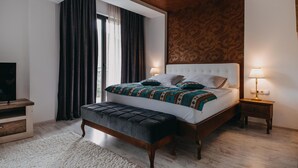 A modern bedroom with a large bed, a bench, two bedside tables, and a TV. - Kostelski Buk Hotel (Bihac)