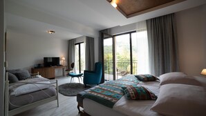 A modern hotel room with a bed, a desk with a TV, a chair, and a balcony with a view. - Kostelski Buk Hotel (Bihac)