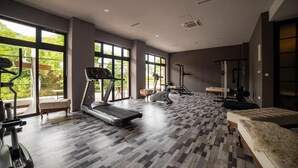 A spacious gym with treadmills, stationary bikes, and weight machines. Large windows offer views of greenery. - Kostelski Buk Hotel (Bihac)