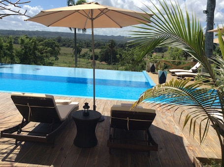 Una piscina al aire libre, sombrillas, sillones reclinables de piscina