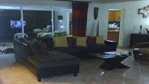 A living room with a large sectional sofa, a coffee table, and a television. - Casa Lilly B&B Cabarete (Cabarete)