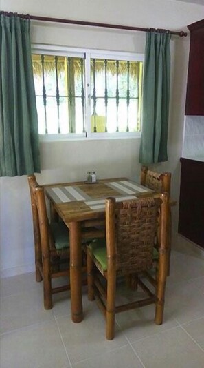 A dining area with a wooden table and chairs, a window with curtains, and a tiled floor. - Casa Lilly B&B Cabarete (Cabarete)